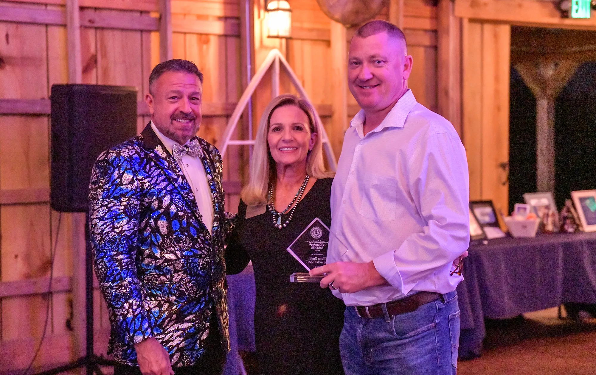 Three well dressed individuals posing with an award