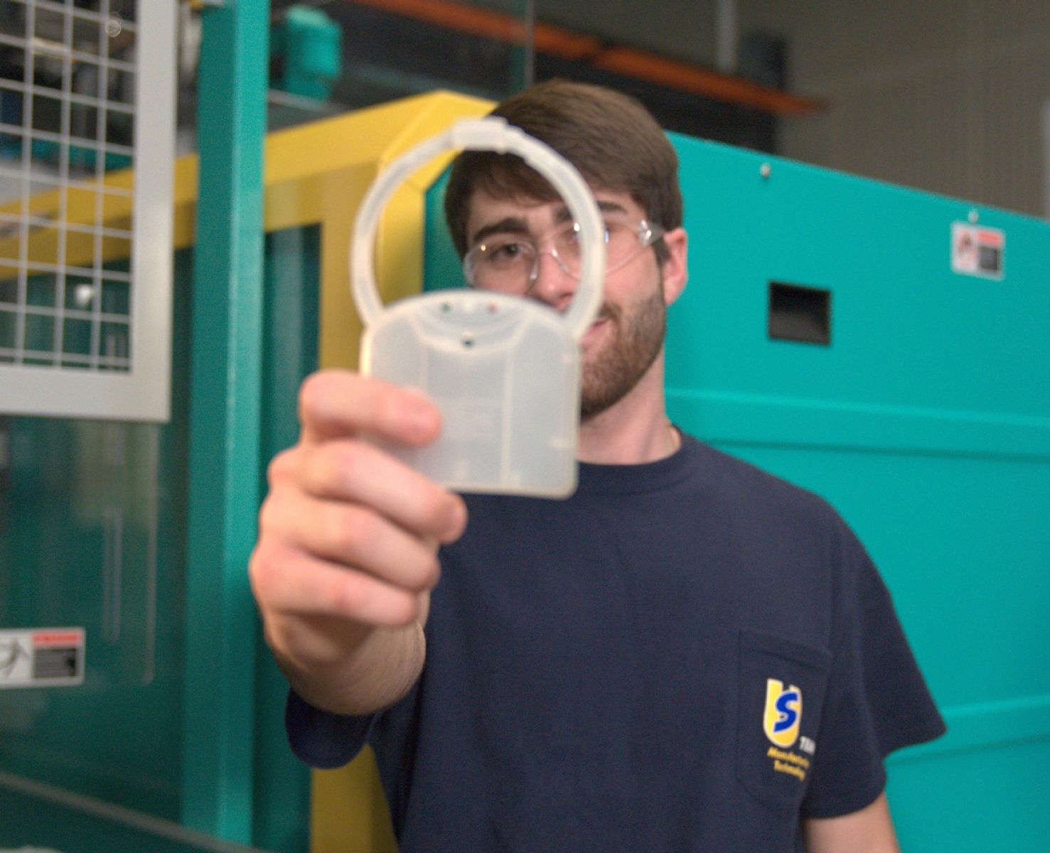 a plastics engineering student holds up a fabricated plastic part